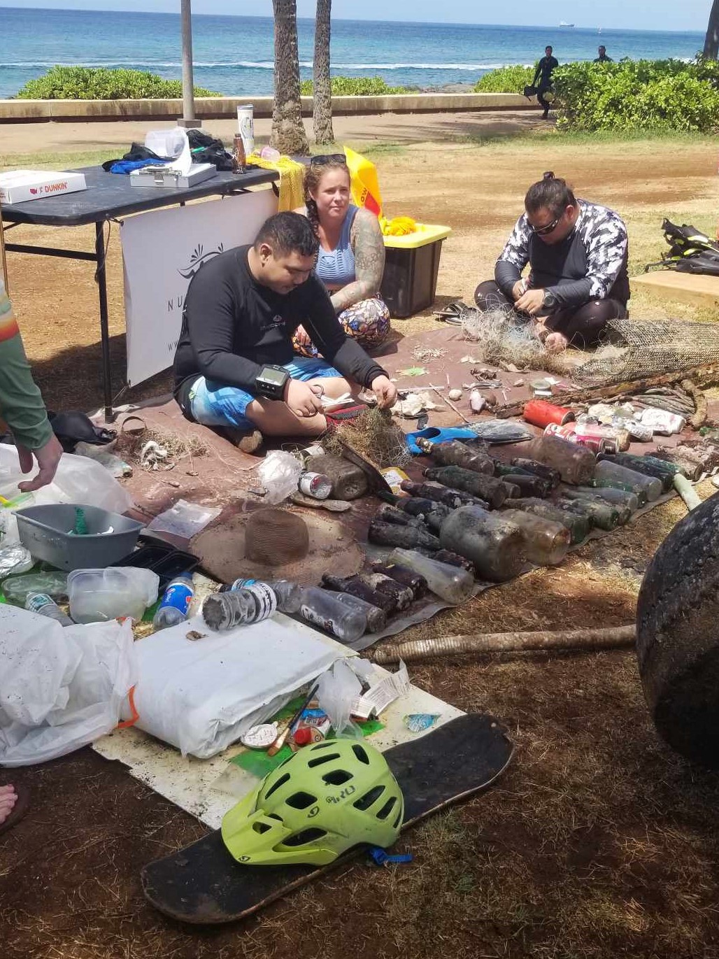 Nudi Wear volunteers sorting debris removed from the ocean in Hawaii