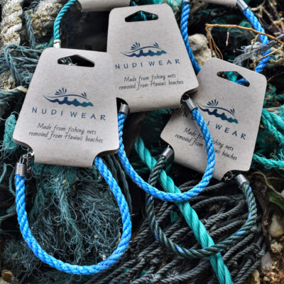 Three of Nudi Wear's fishing net bracelets are displayed on top of some fishing line. Each bracelet is a slightly different color as they are made from retrieved ghost fishing gear. 
