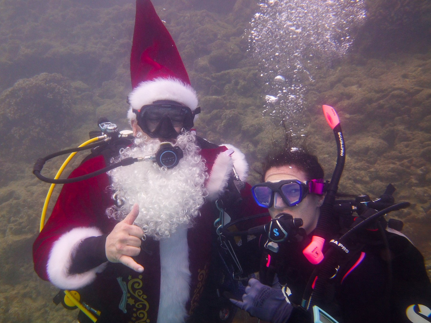 SCUBA Santa and volunteer diver posing underwater with shakas at the Nudi Wear cleanup dive