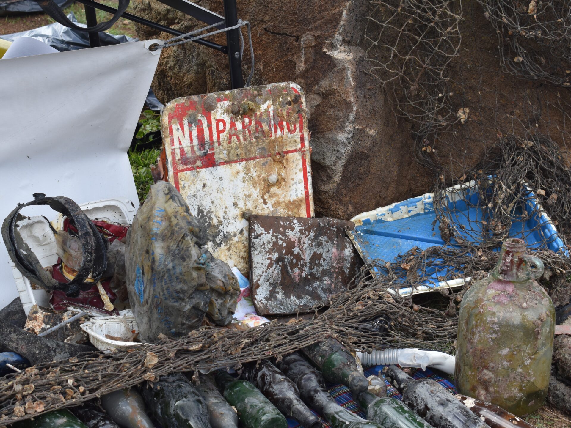trash on the ground on a tarp that was removed from the ocean during the Nudi Wear cleanup dive with santa