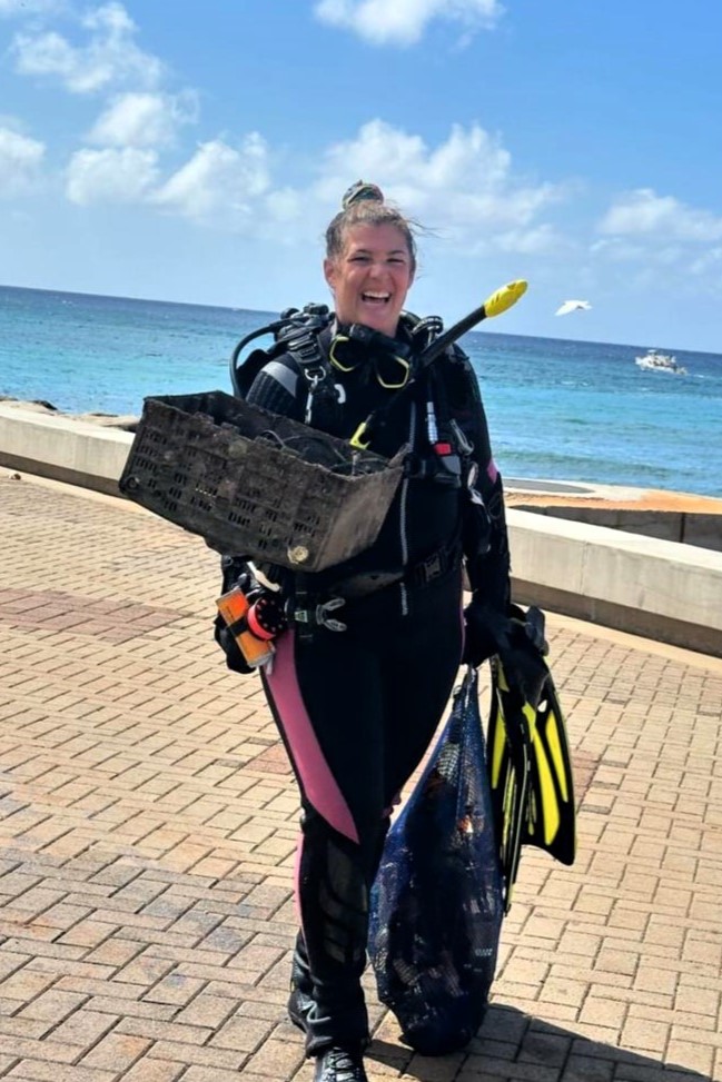 A Nudi Wear volunteer diver carrying a TV she removed from the ocean.