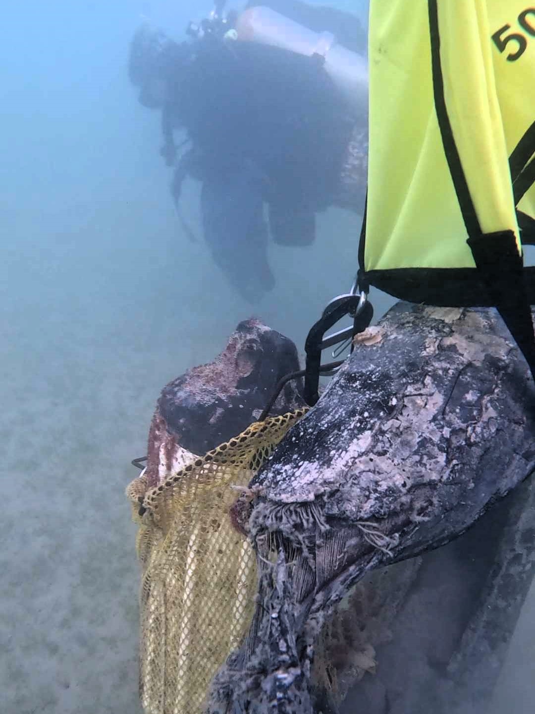 A tire and float being remove from the ocean with a lift bag