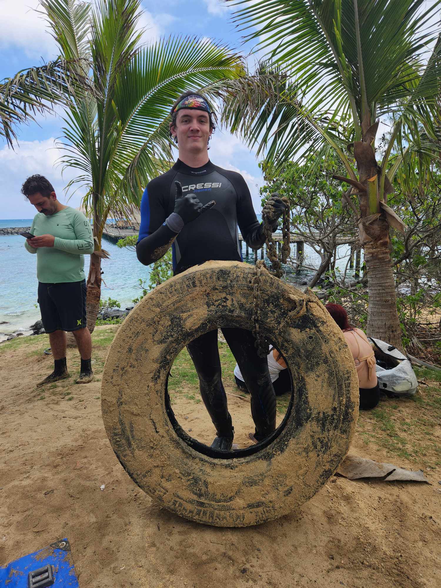 Diver posing with large tire removed from the ocean around the Makai Research PIer