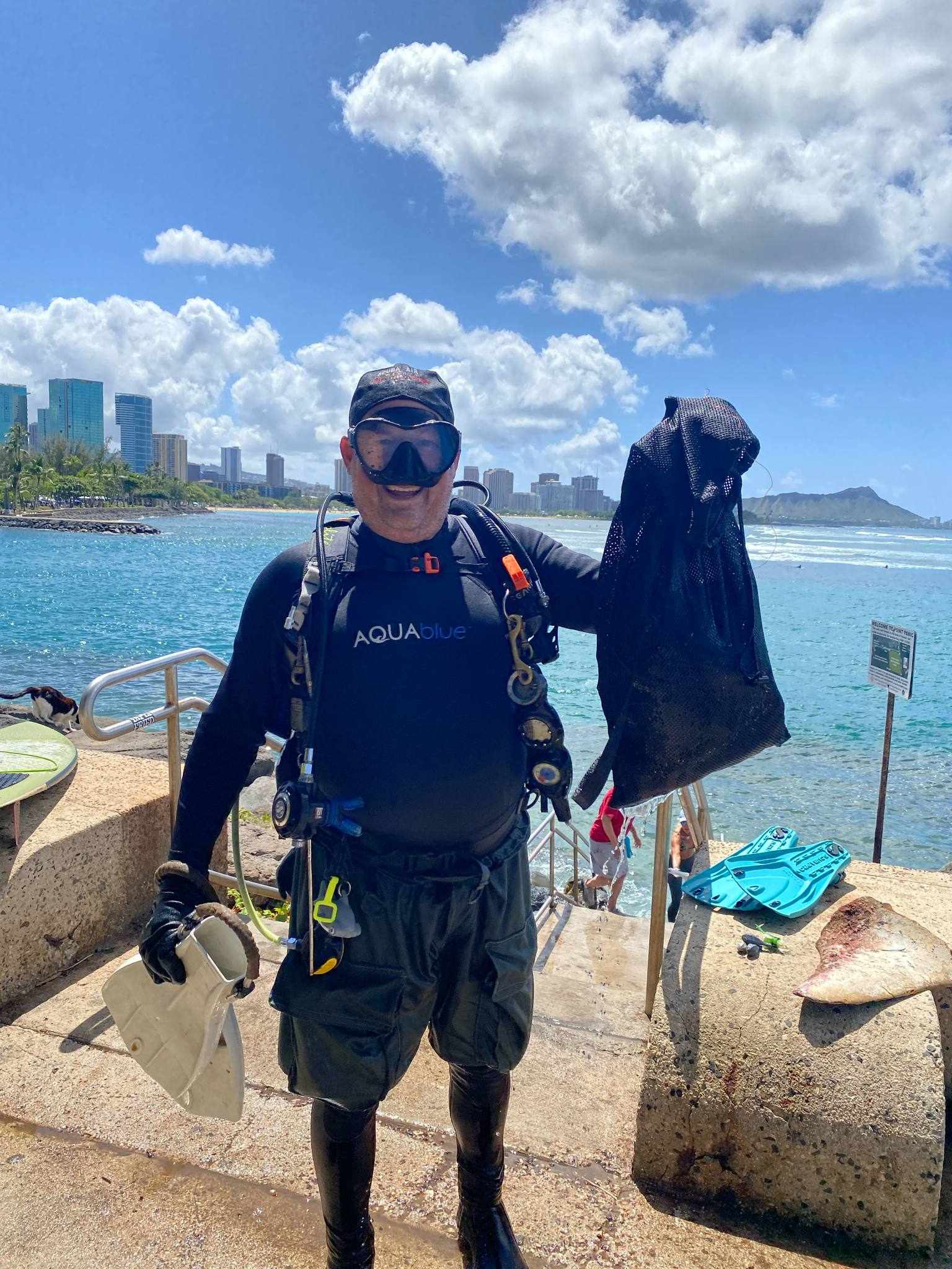 A diver holding up his bag full of marine debris