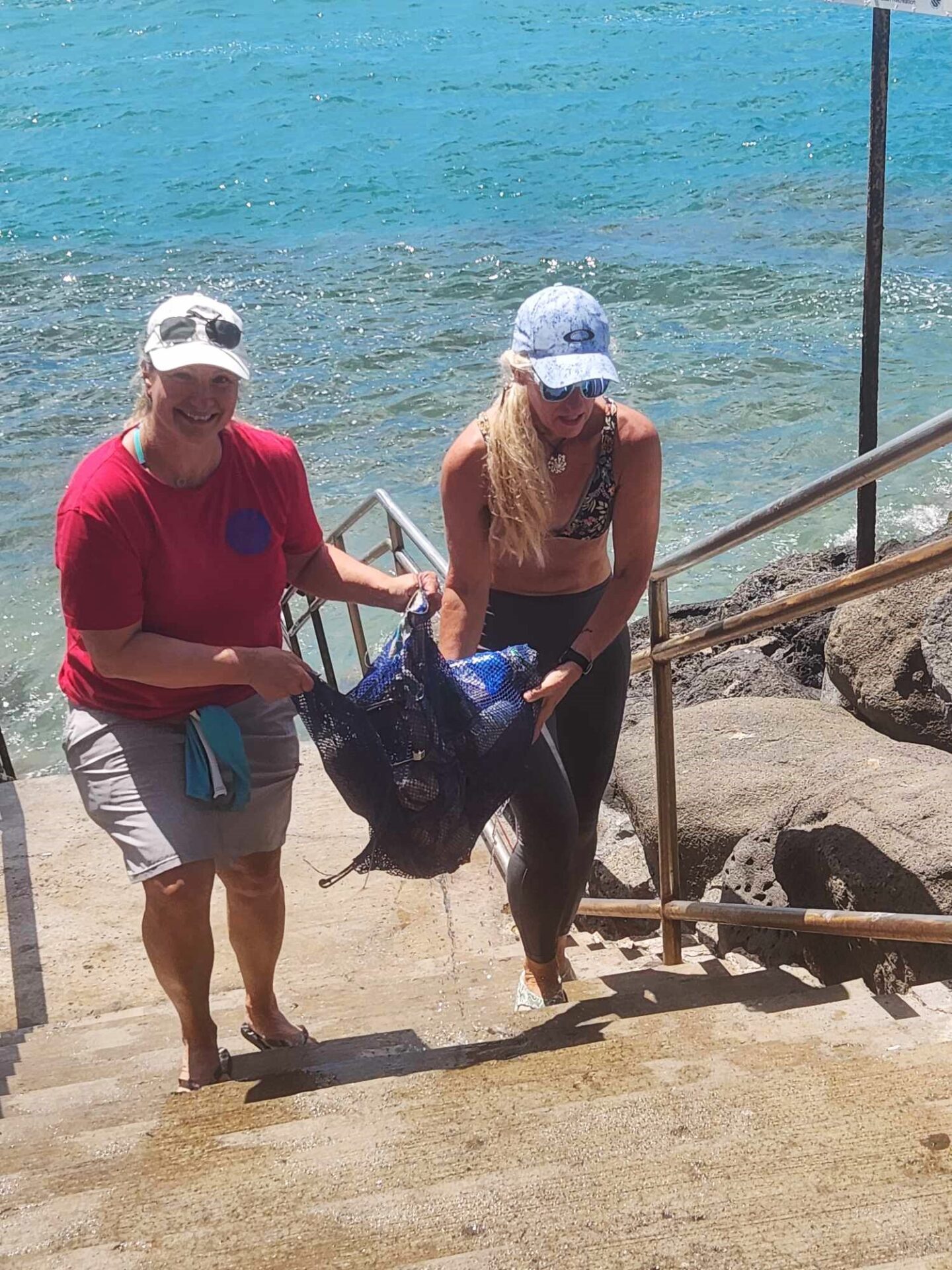 Volunteers helping the divers lift heaving bags of marine debris out of the ocean and up the stairs